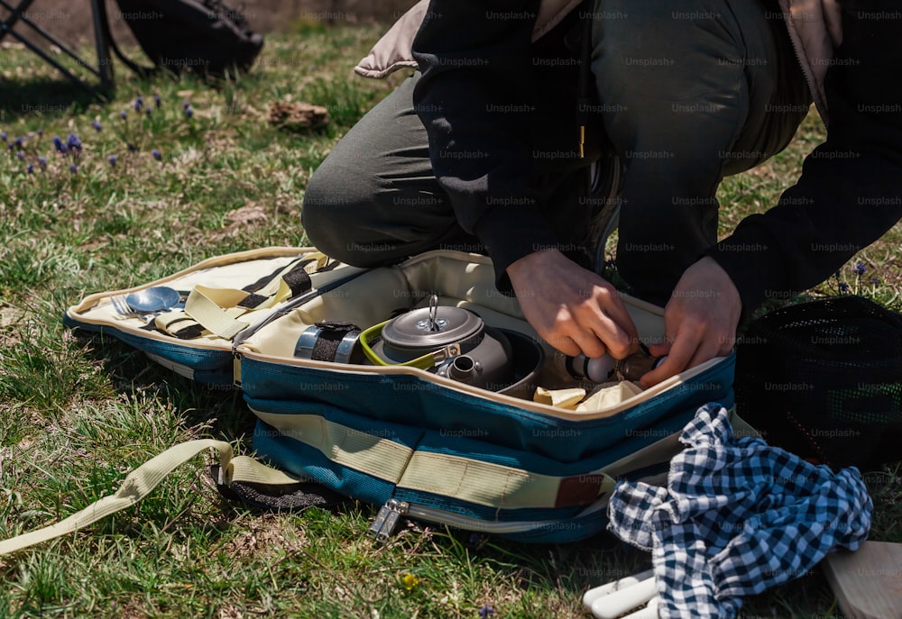 a person kneeling down with a piece of luggage on the ground