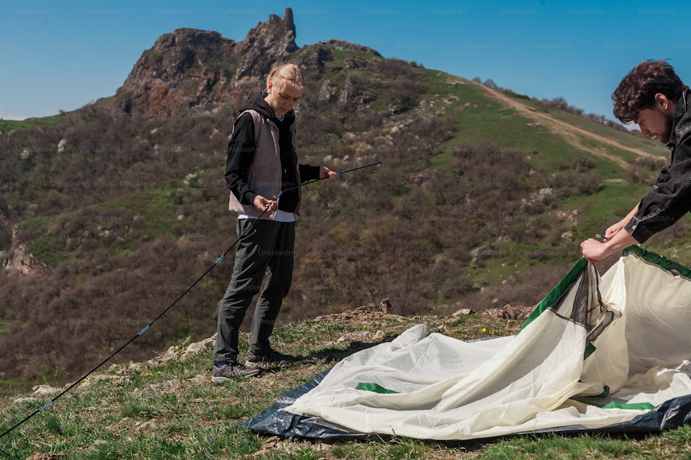 a man and a woman setting up a tent on top of a mountain