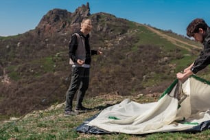 a man and a woman setting up a tent on top of a mountain