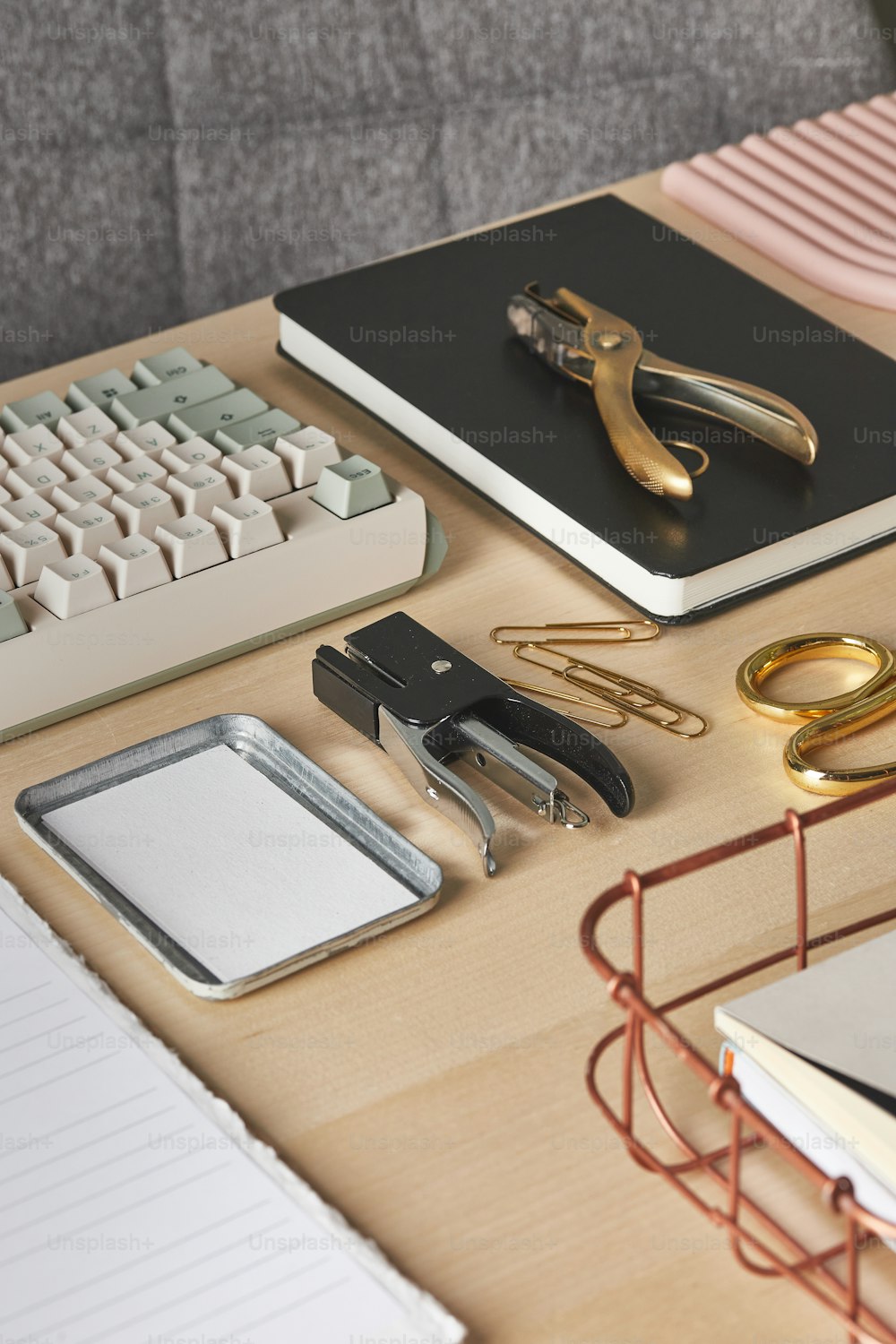 a desk with a keyboard, binder, scissors, and other office supplies