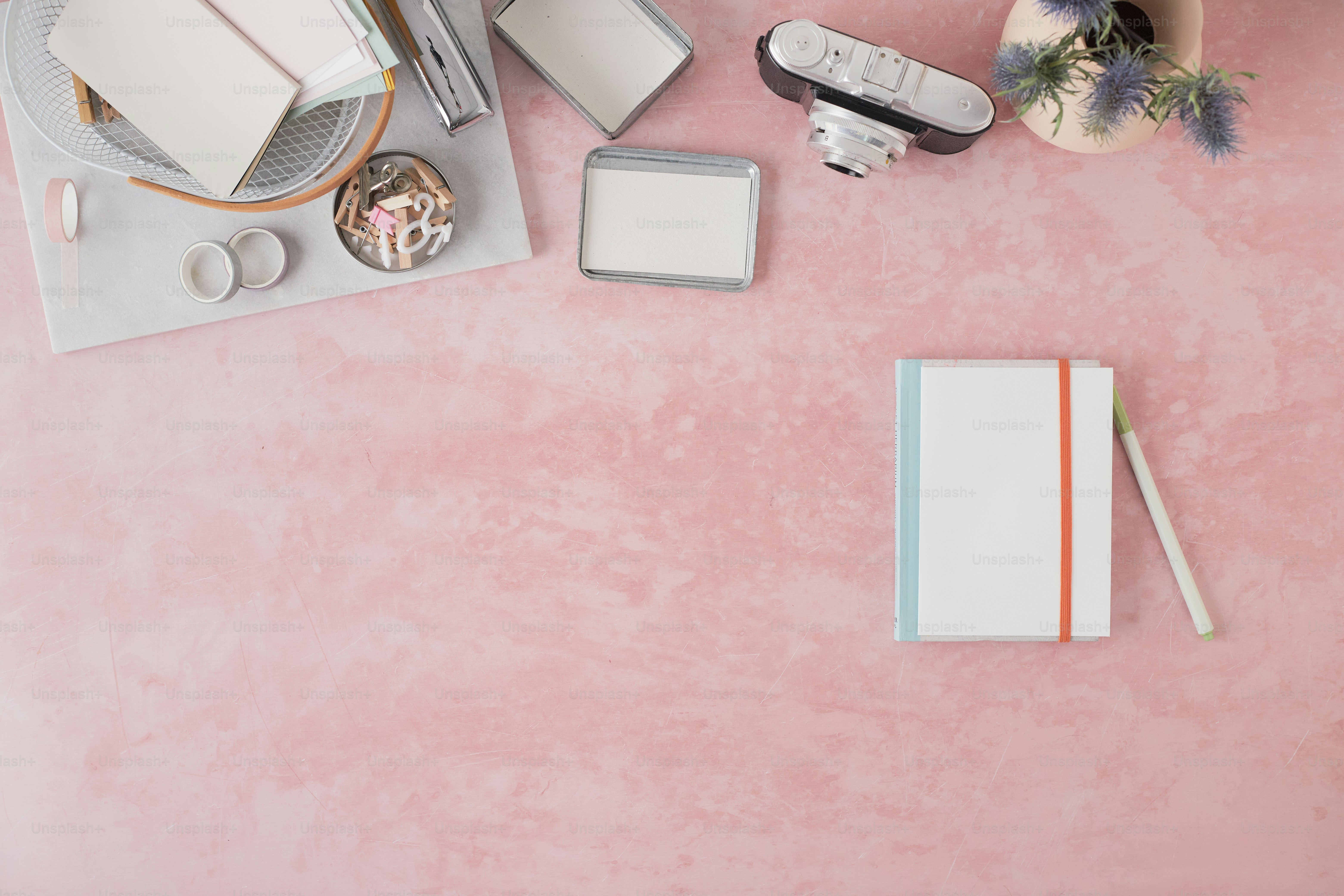 a table topped with a laptop computer next to a pink wall