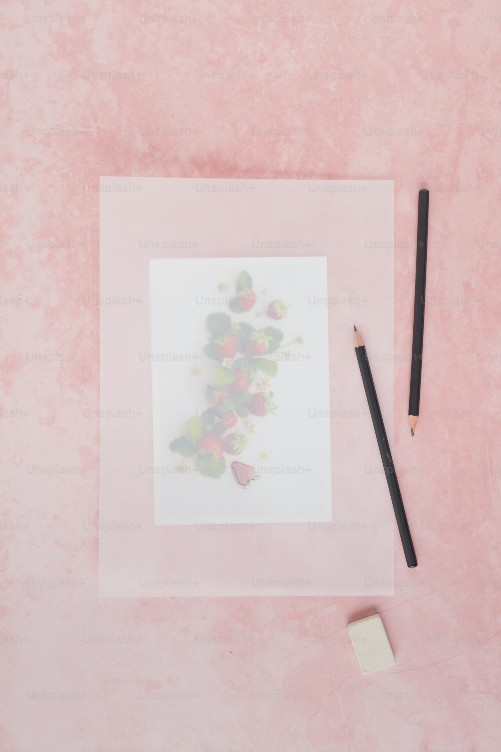 una matita e un disegno su una superficie rosa