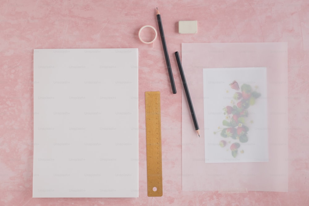 uma mesa rosa com uma tesoura e um papel em branco