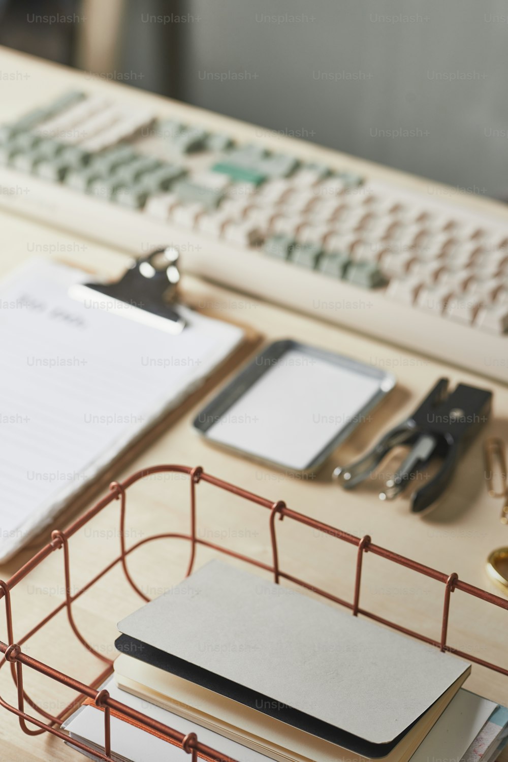 un escritorio con un teclado de computadora, cuaderno y otros suministros de oficina