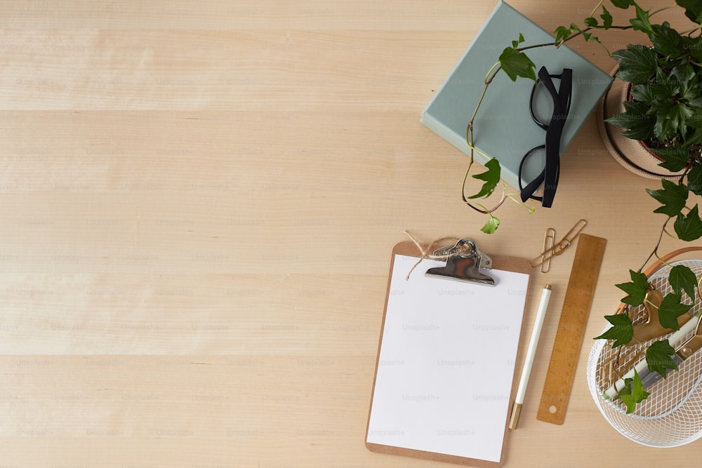 a clipboard with a pen and glasses on it next to a potted plant