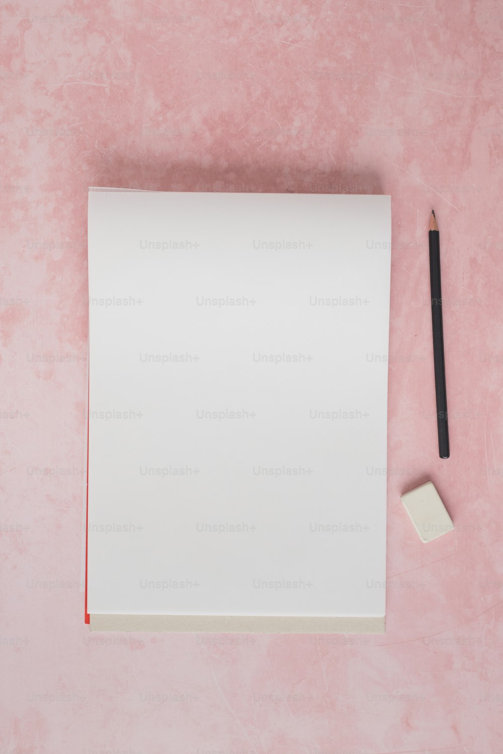 um pedaço de papel e um lápis sobre uma superfície rosa