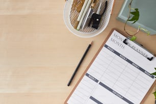 a wooden table with a clipboard, pen, and planner