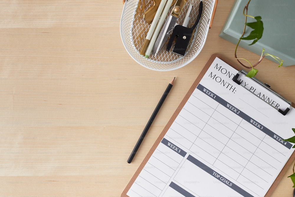 a wooden table with a clipboard, pen, and planner