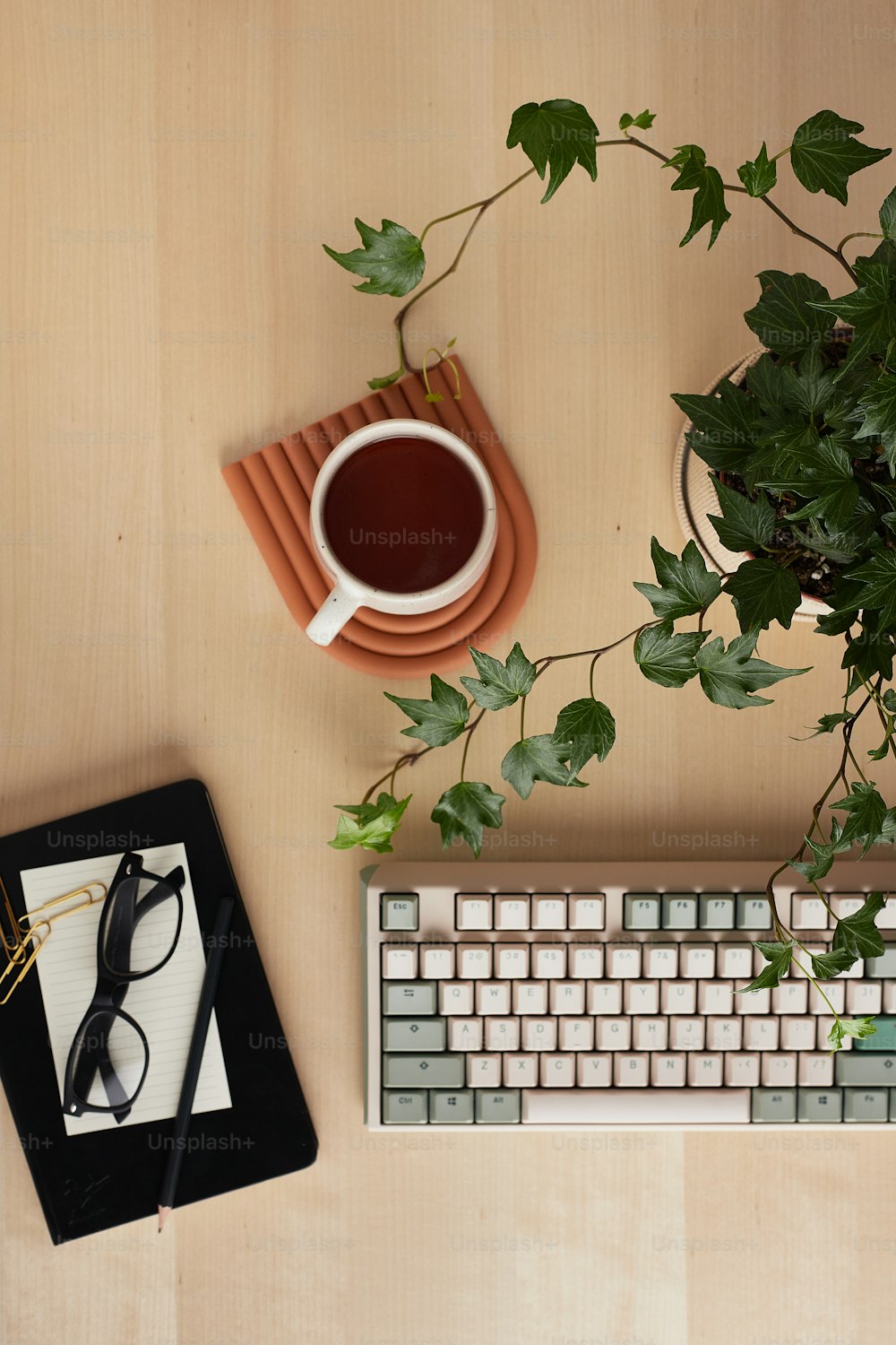 a desk with a keyboard, mouse and a plant