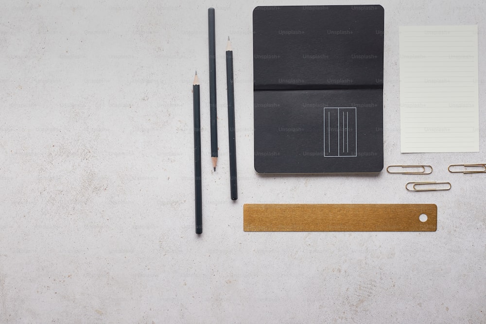 a notepad, pen, pencil, and paper clips on a table