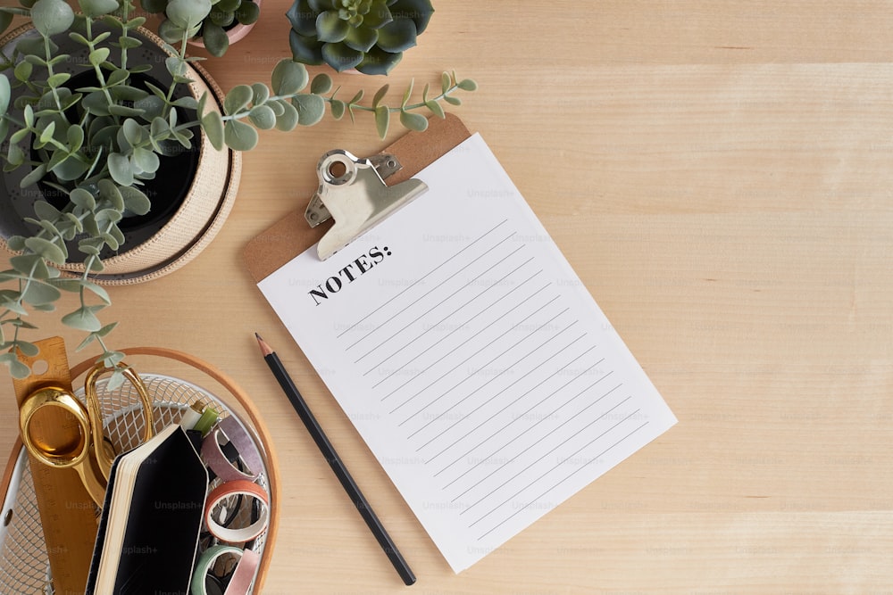 a notepad sitting on top of a wooden table next to a plant