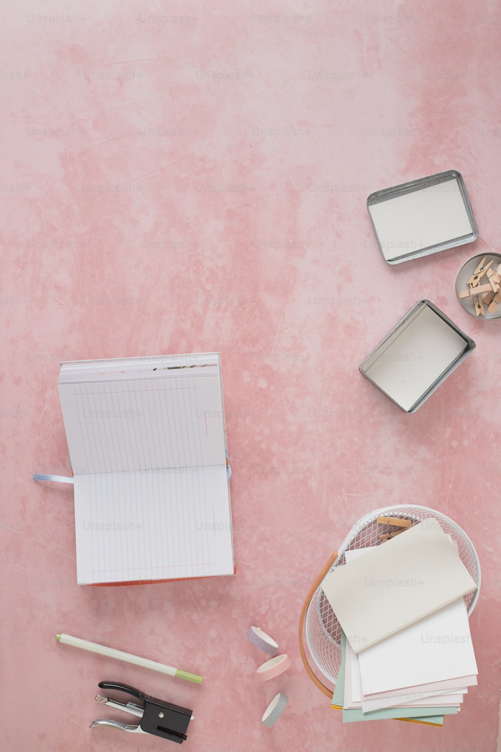 a pink table with a notebook, pen, mirror and other items