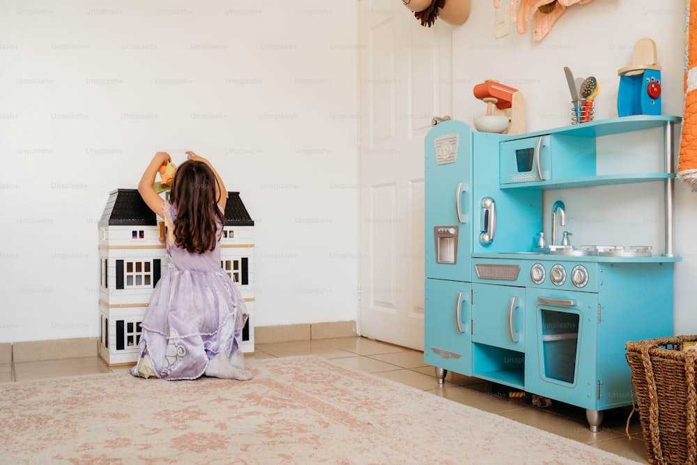 a little girl sitting on the floor in front of a toy stove