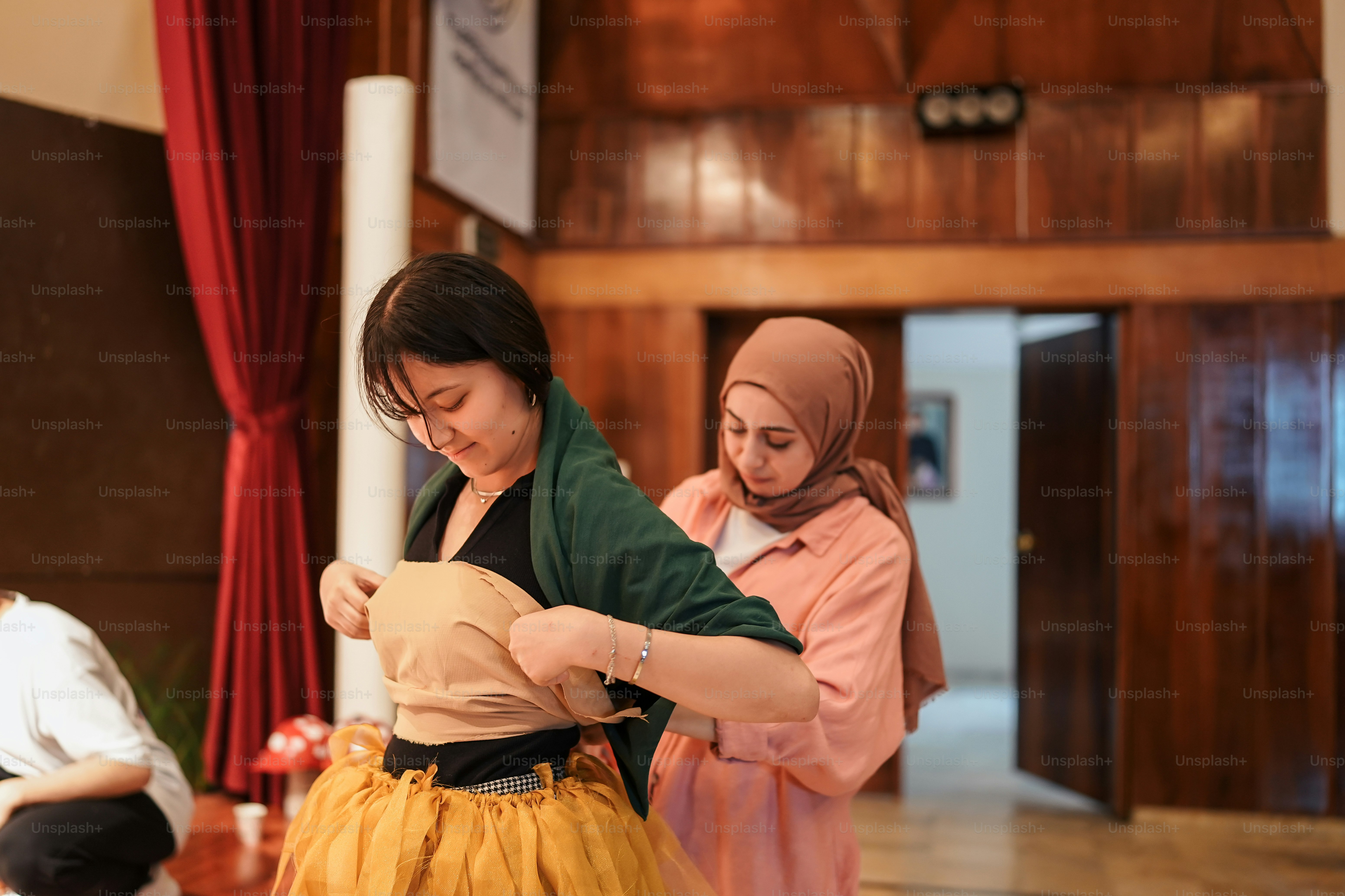 two women in hijabs are looking at a piece of paper