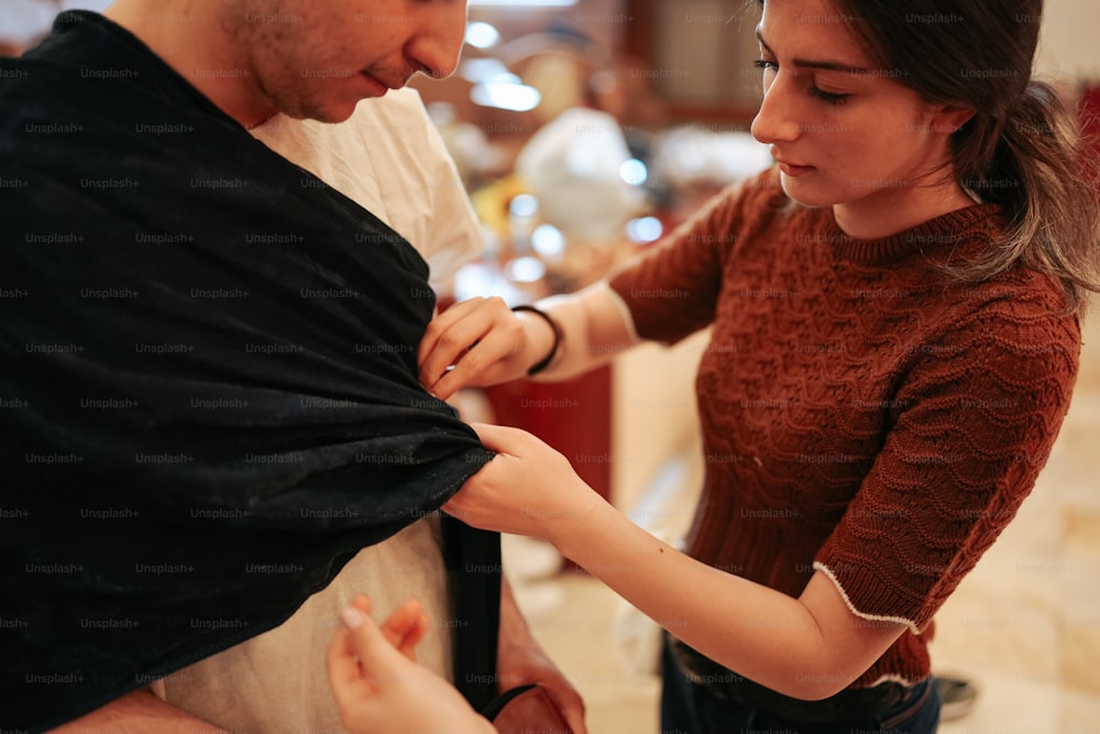 a man helping a woman put on a scarf