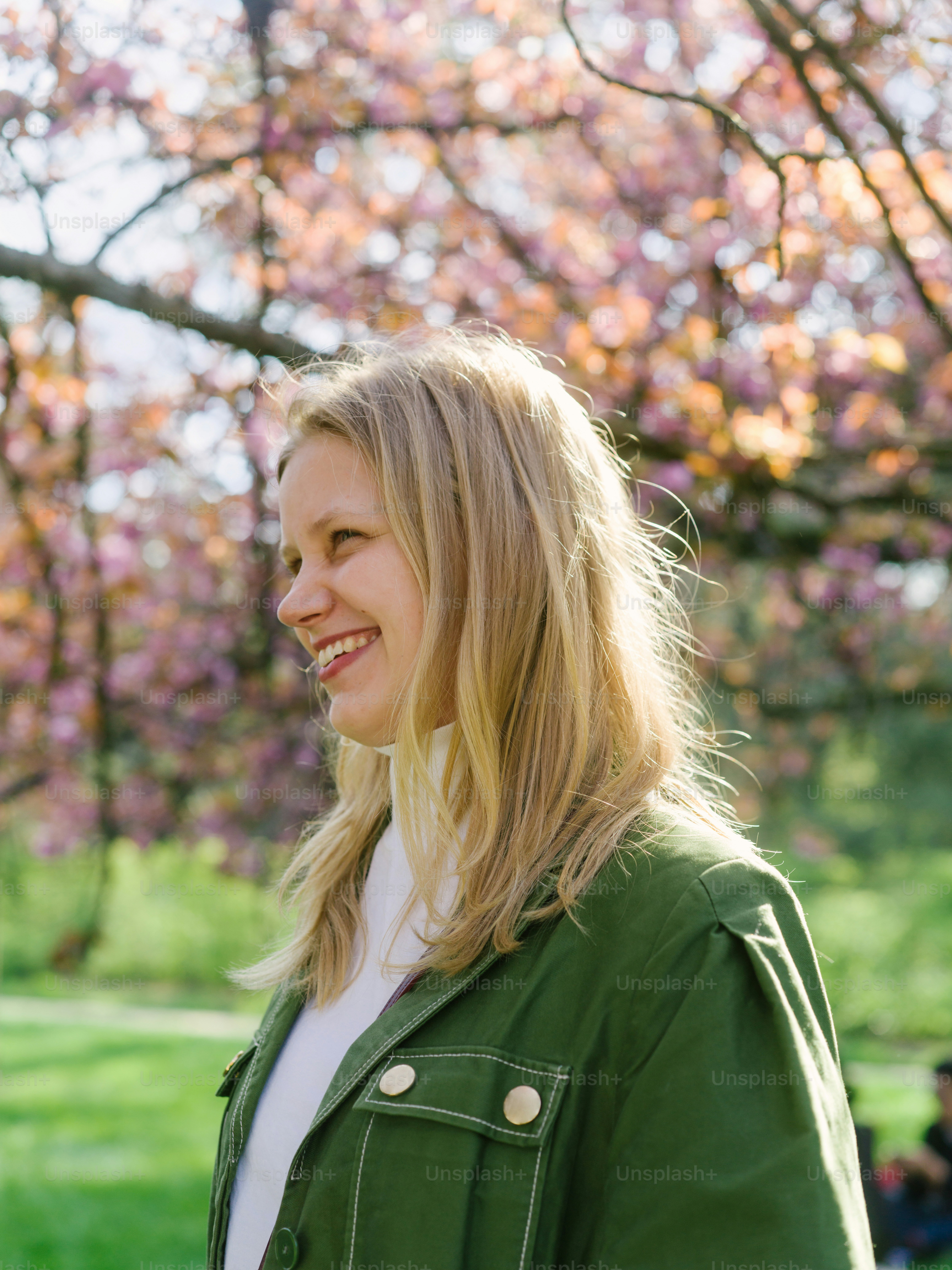 a woman in a green jacket standing in front of a tree