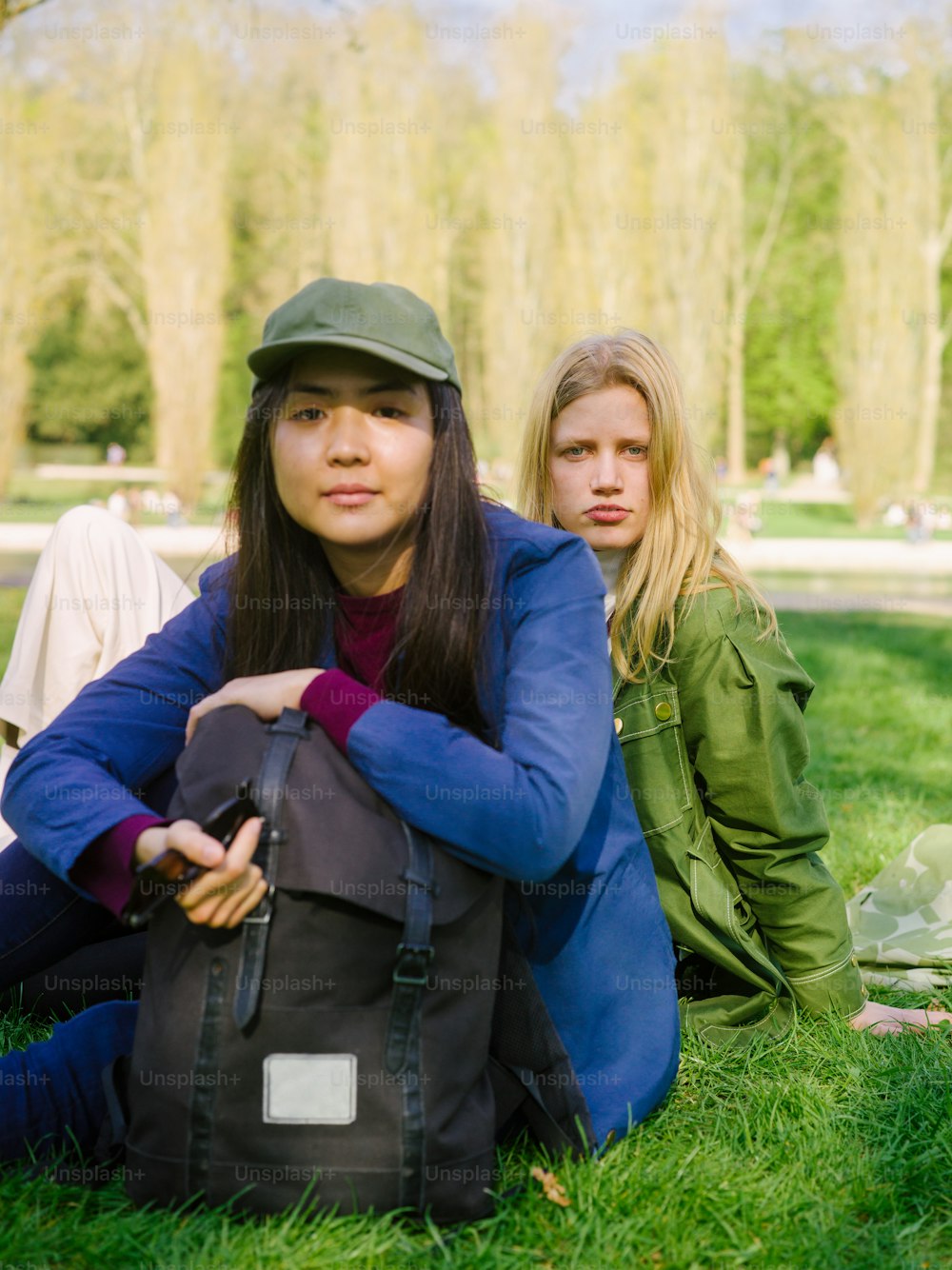 two young women sitting on the grass in a park