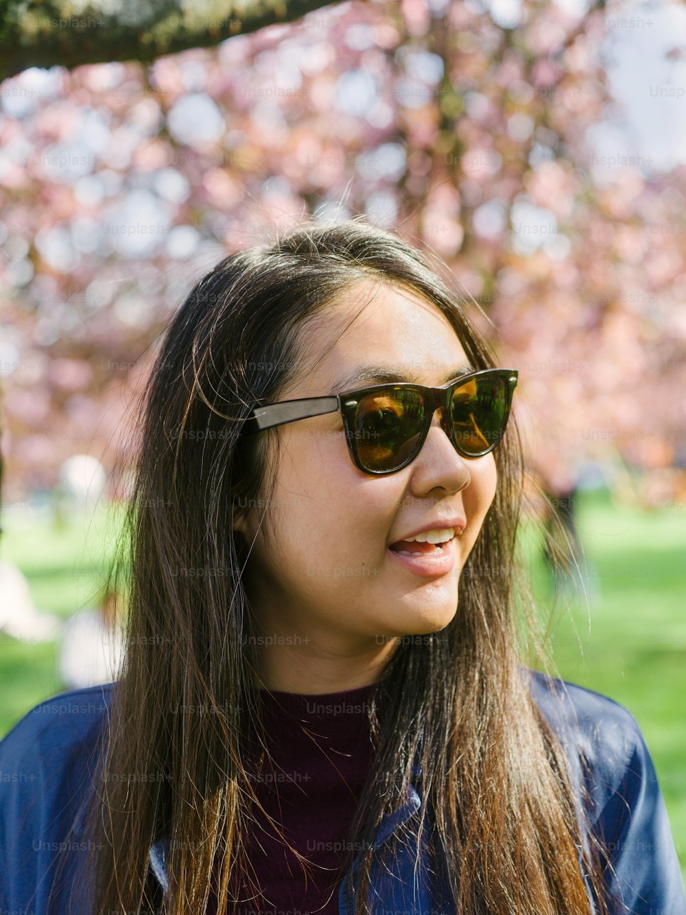 a woman wearing sunglasses standing in front of a tree