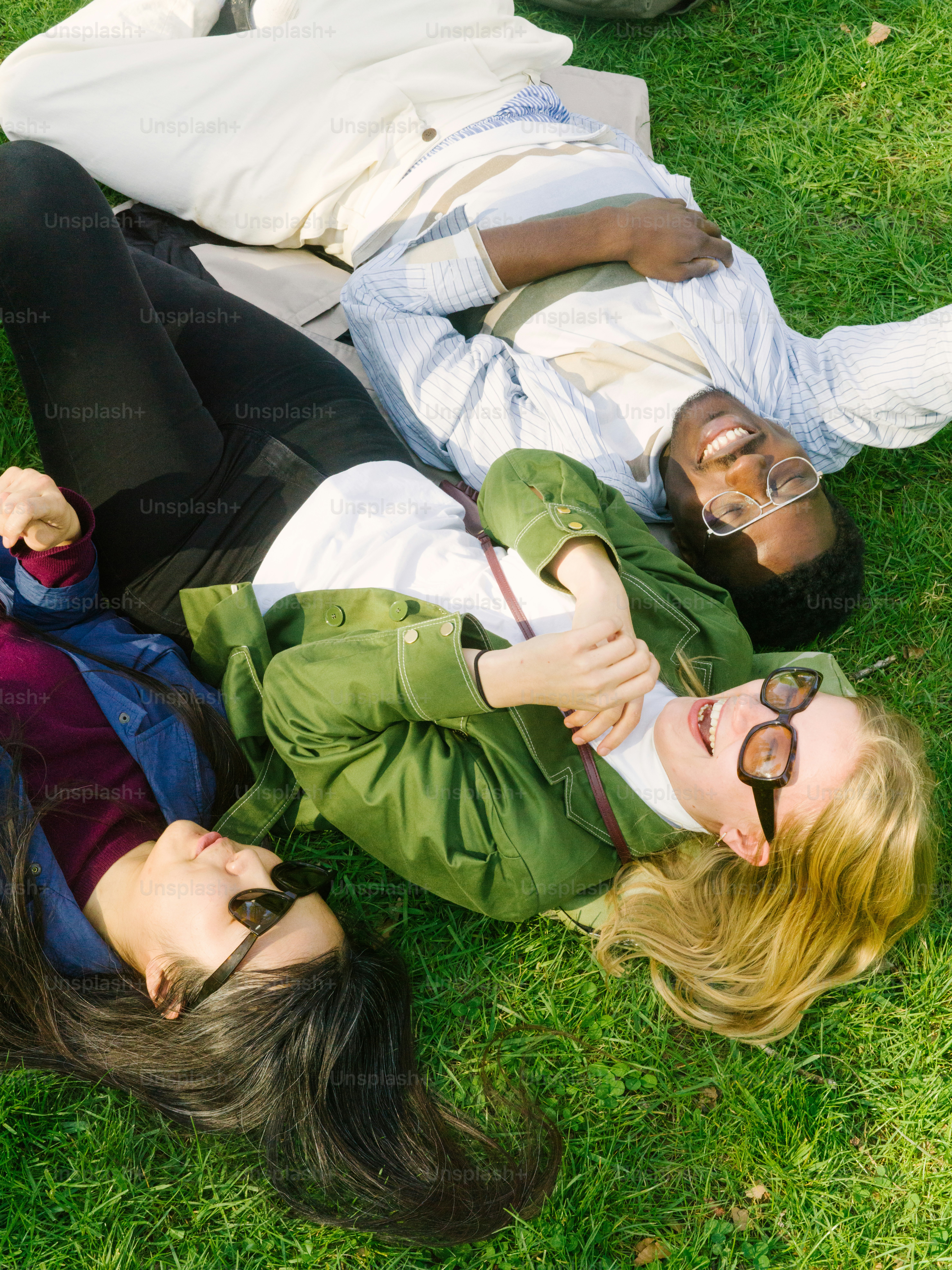 a couple of people laying on top of a lush green field