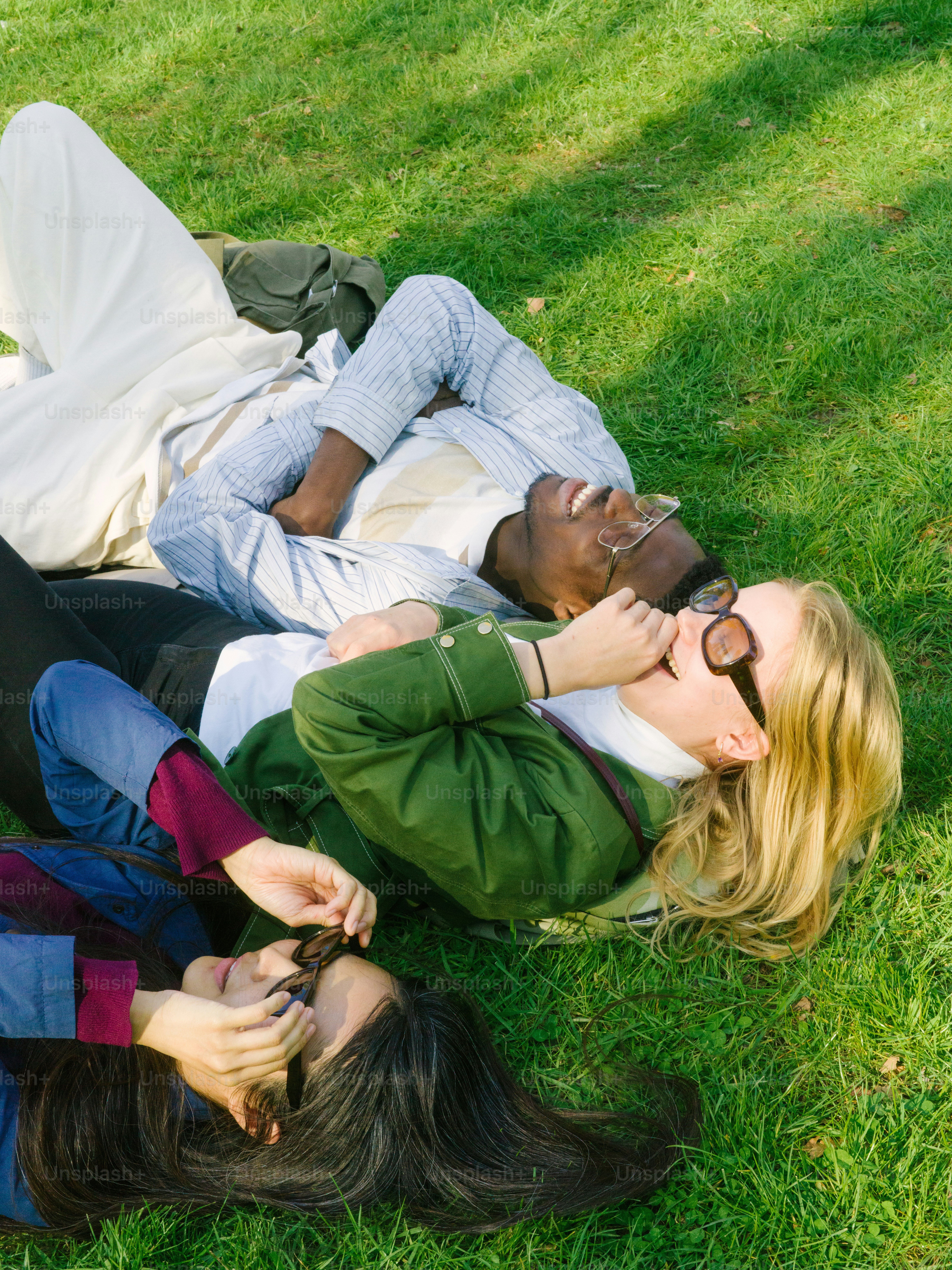 a couple of people laying on top of a lush green field