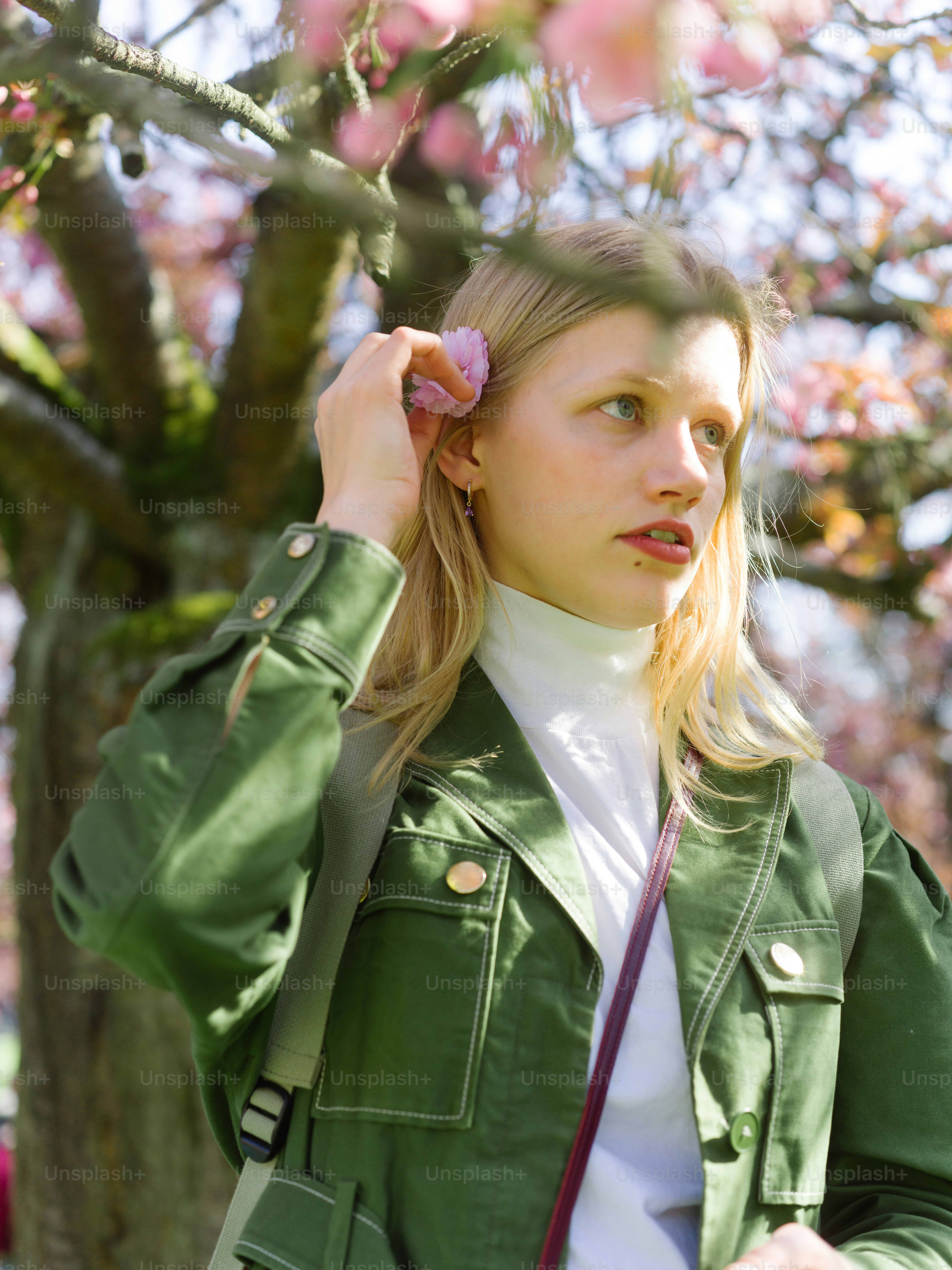 A woman in a green jacket holding a pink flower photo – Portrait Image ...