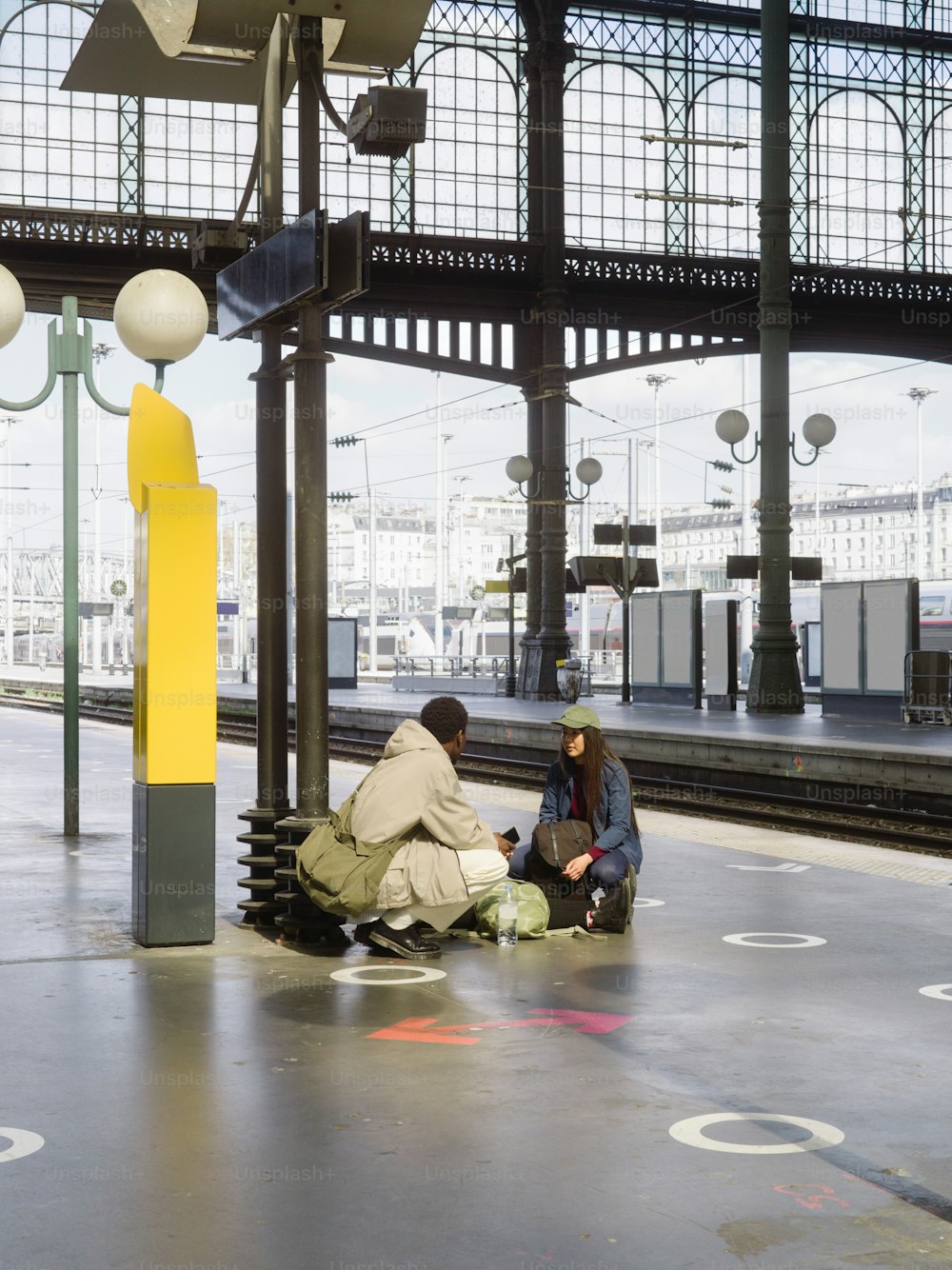 duas pessoas sentadas em um banco em uma estação de trem