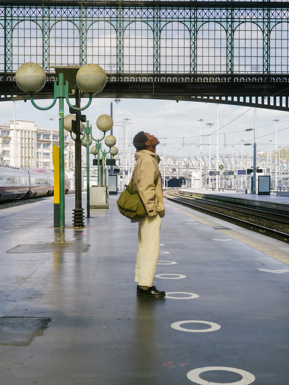 a man standing at a train station waiting for a train