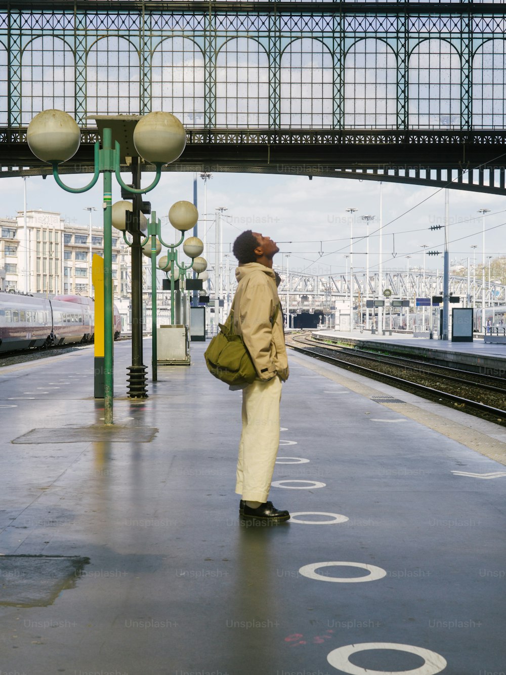 a man standing at a train station waiting for a train