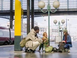 a group of people sitting on the ground next to a train