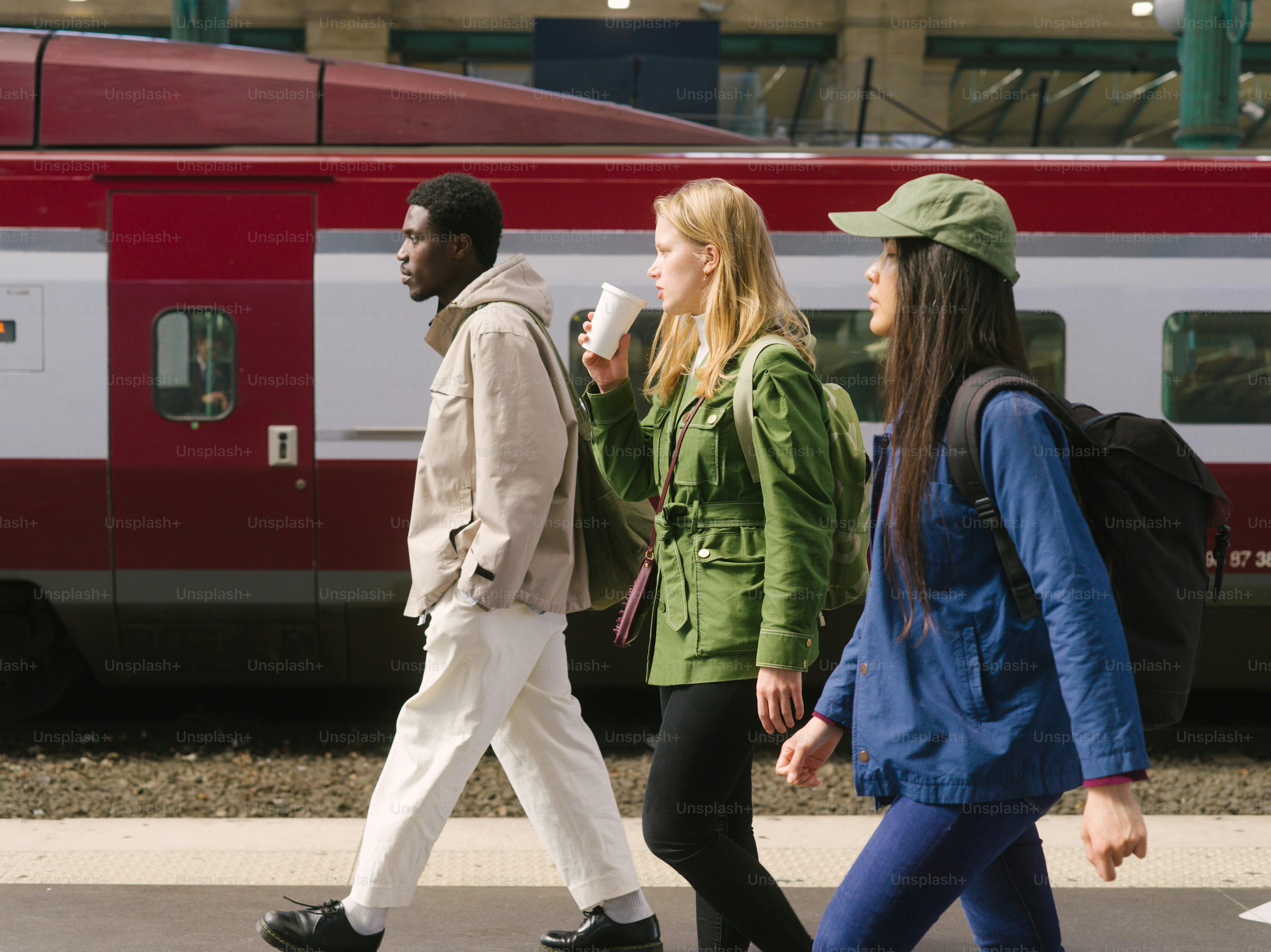 a group of people walking across a street next to a train
