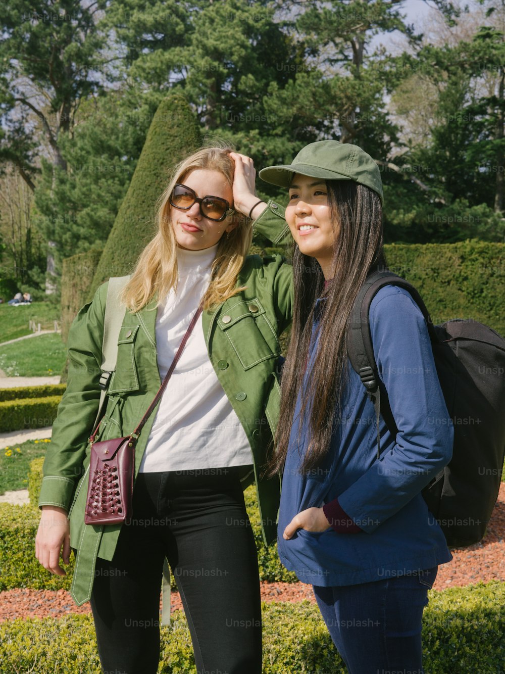 two women standing next to each other in a park