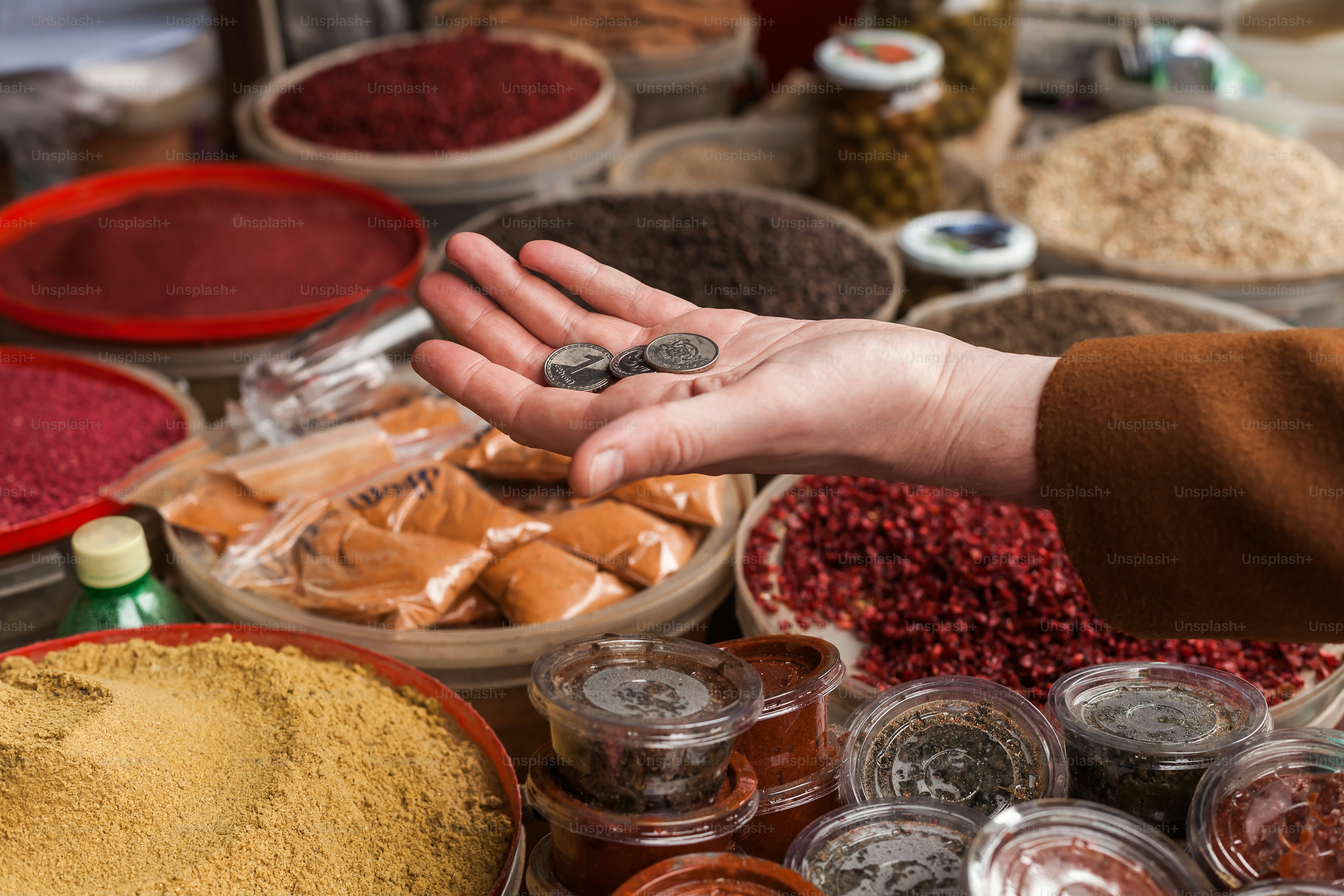 a mão de uma pessoa alcançando uma moeda na frente de uma variedade de especiarias