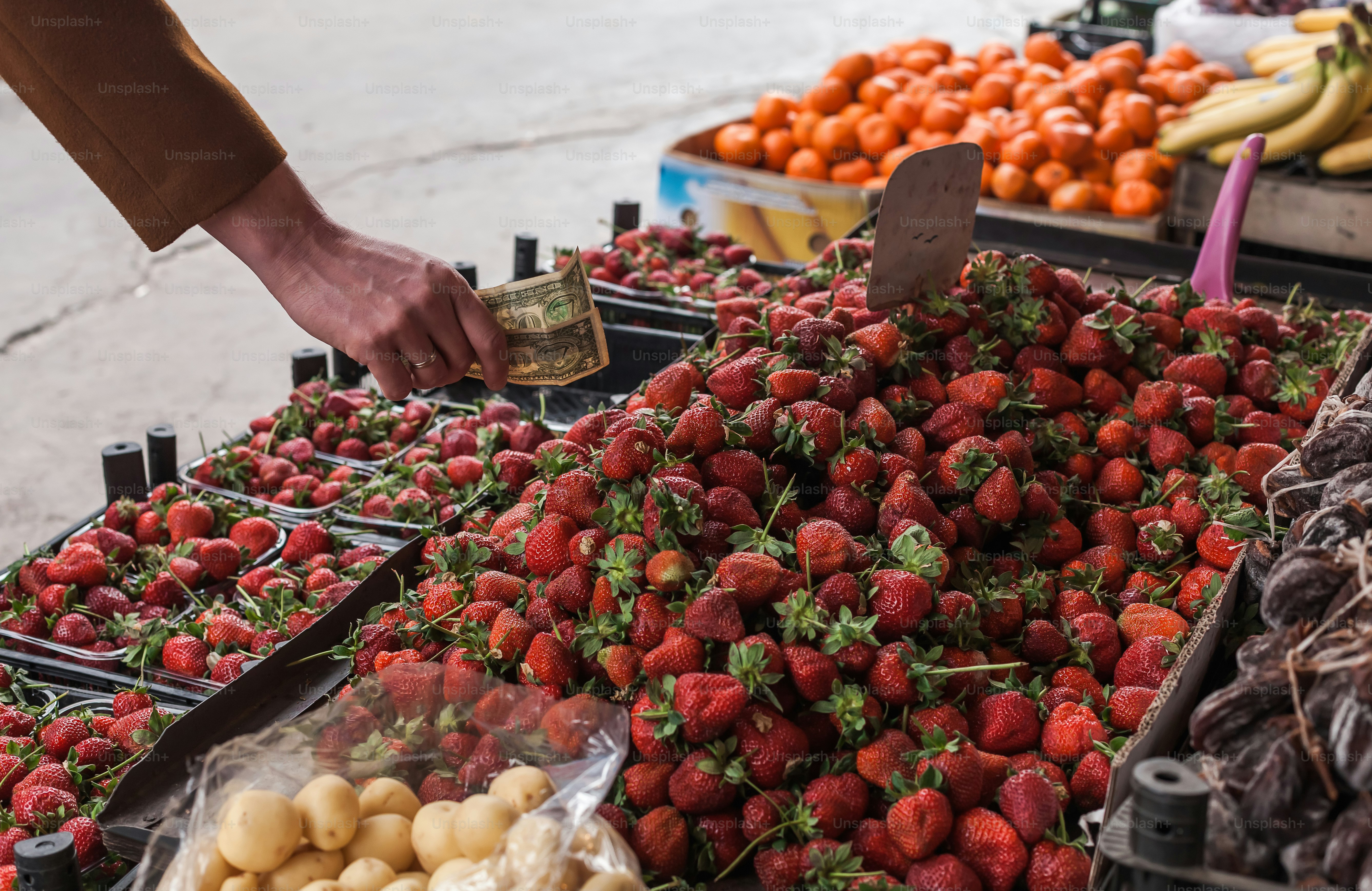 uma pessoa está pegando morangos em uma banca de frutas