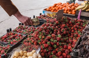 a person is picking up strawberries at a fruit stand