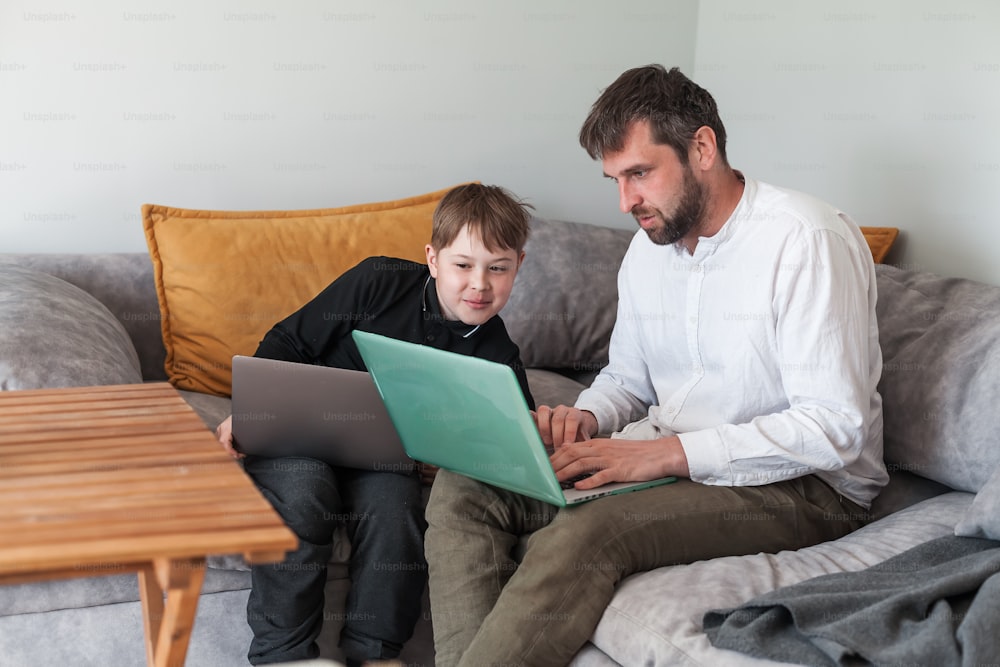 a man and a boy sitting on a couch with a laptop