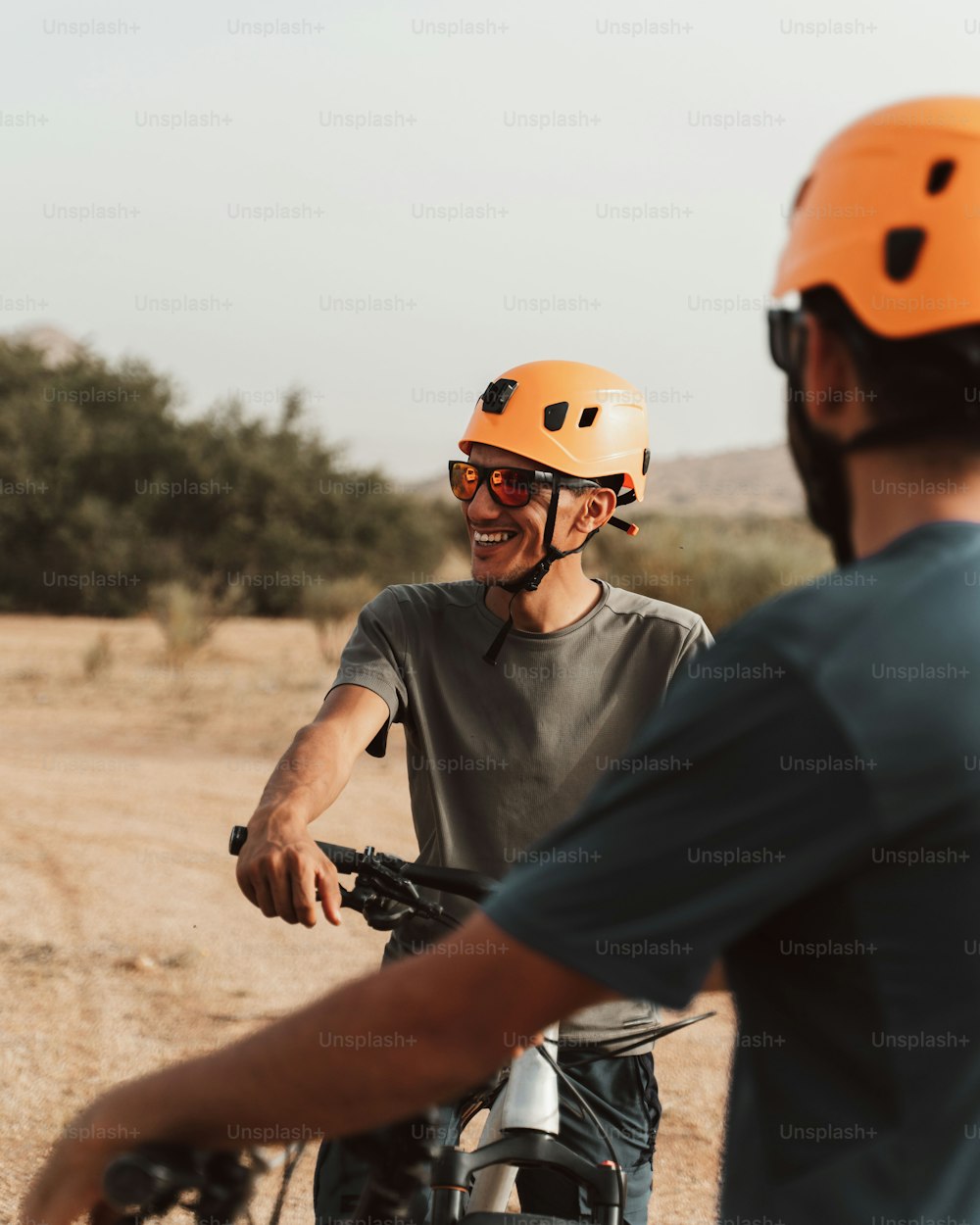 a couple of men riding bikes down a dirt road