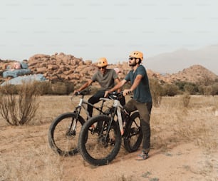 a couple of men standing next to each other on bikes