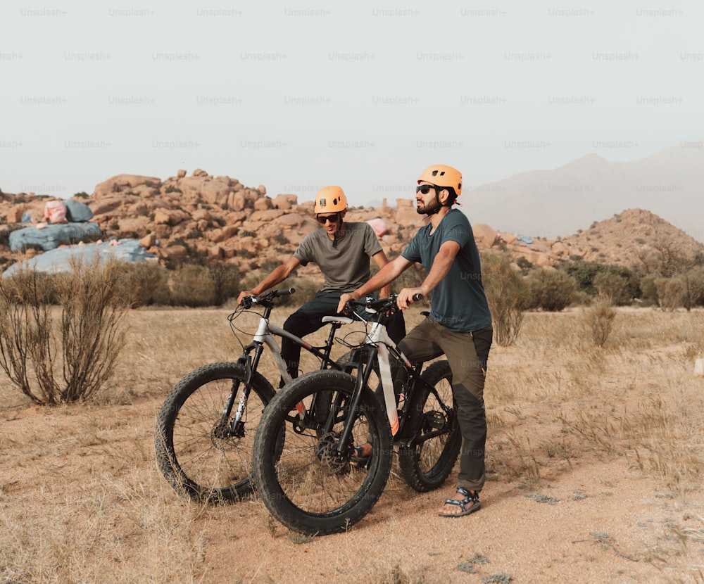 a couple of men standing next to each other on bikes