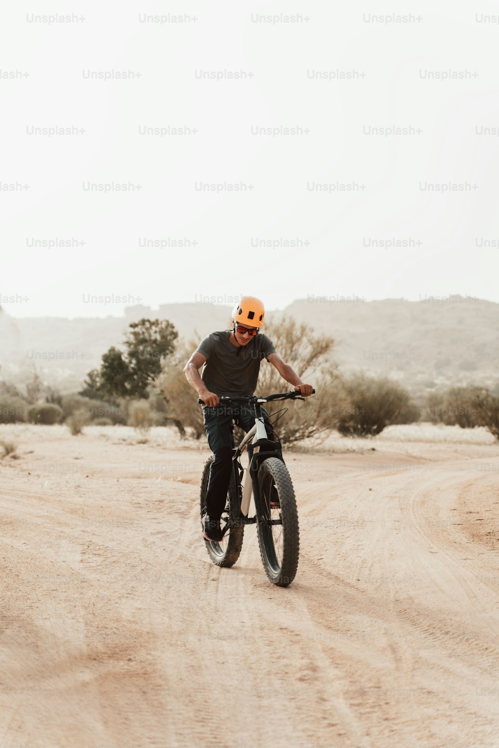 um homem andando de bicicleta por uma estrada de terra
