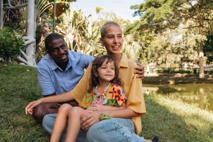 Un homme et une femme assis sur l’herbe avec une petite fille