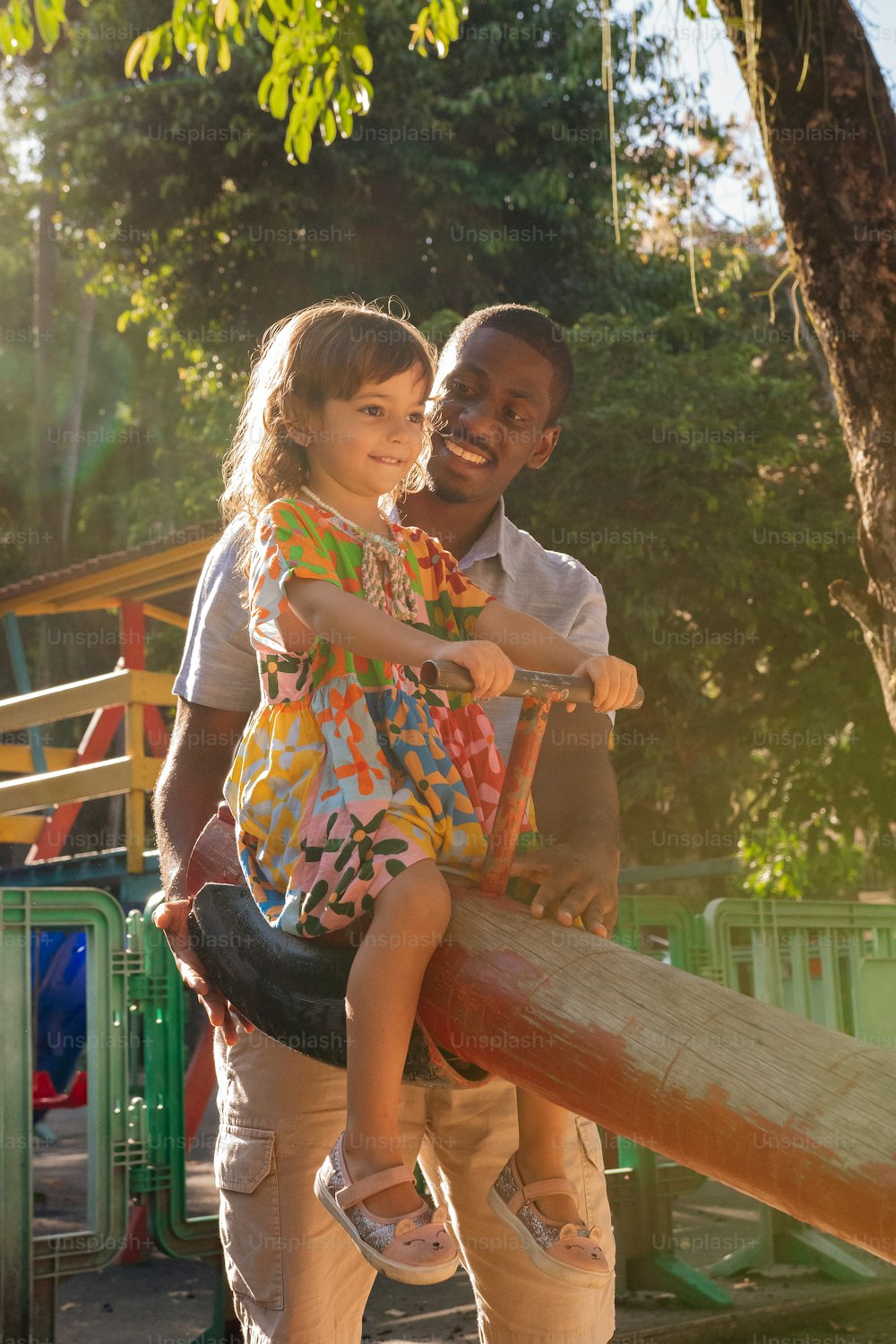 a man holding a little girl on top of a wooden slide