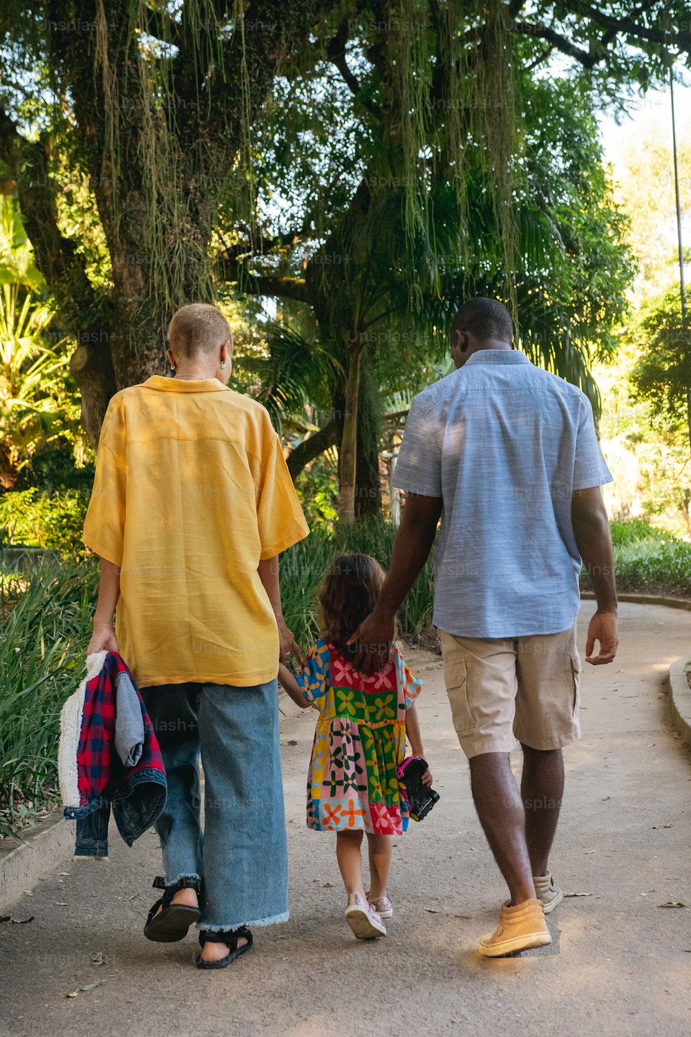 um homem e duas crianças caminhando por um caminho