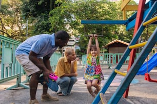 Un homme et deux enfants jouent sur une aire de jeux