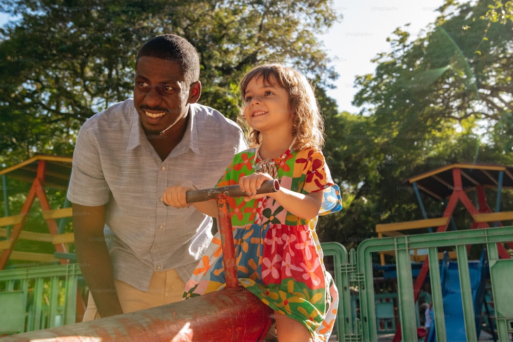 a man and a little girl playing in a playground