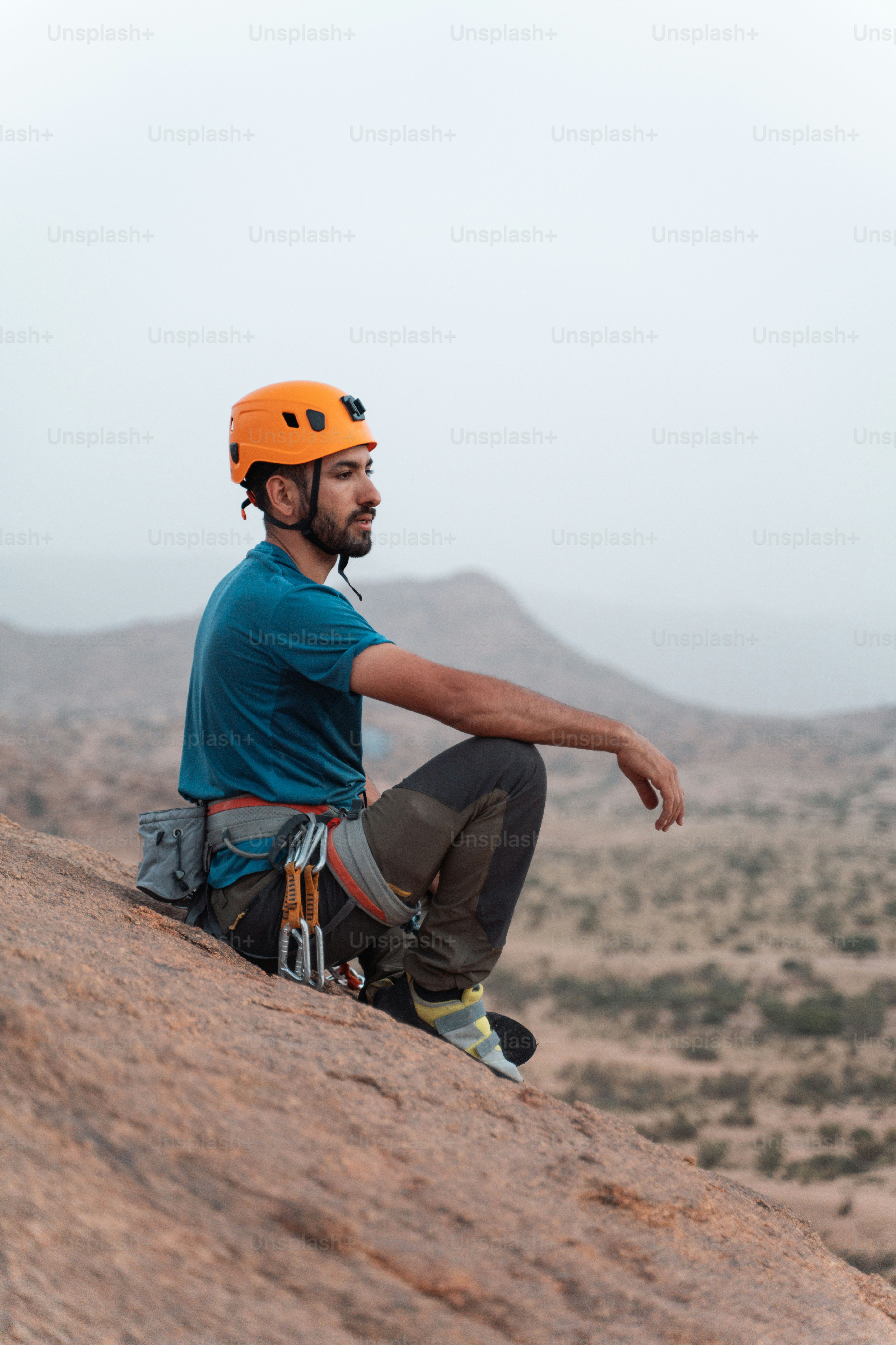 Un hombre sentado en la cima de una roca con un casco puesto