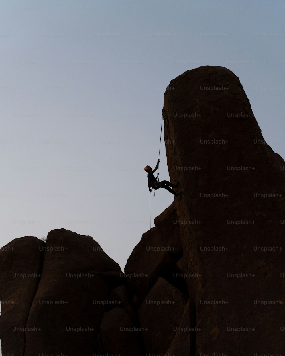 um homem subindo o lado de uma grande rocha