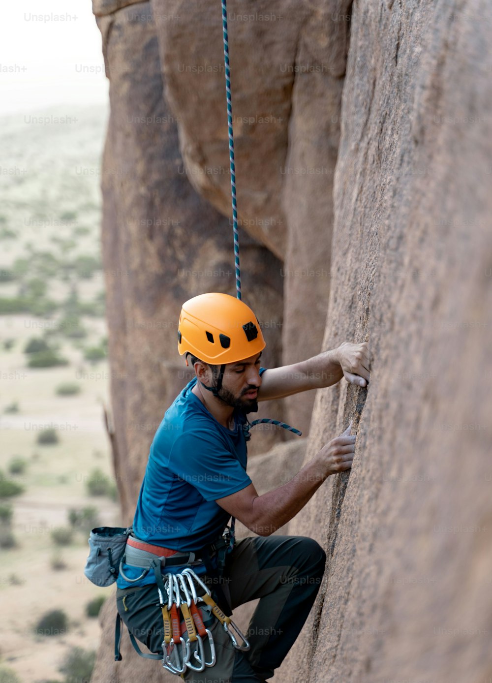 Un uomo che si arrampica sul fianco di una roccia