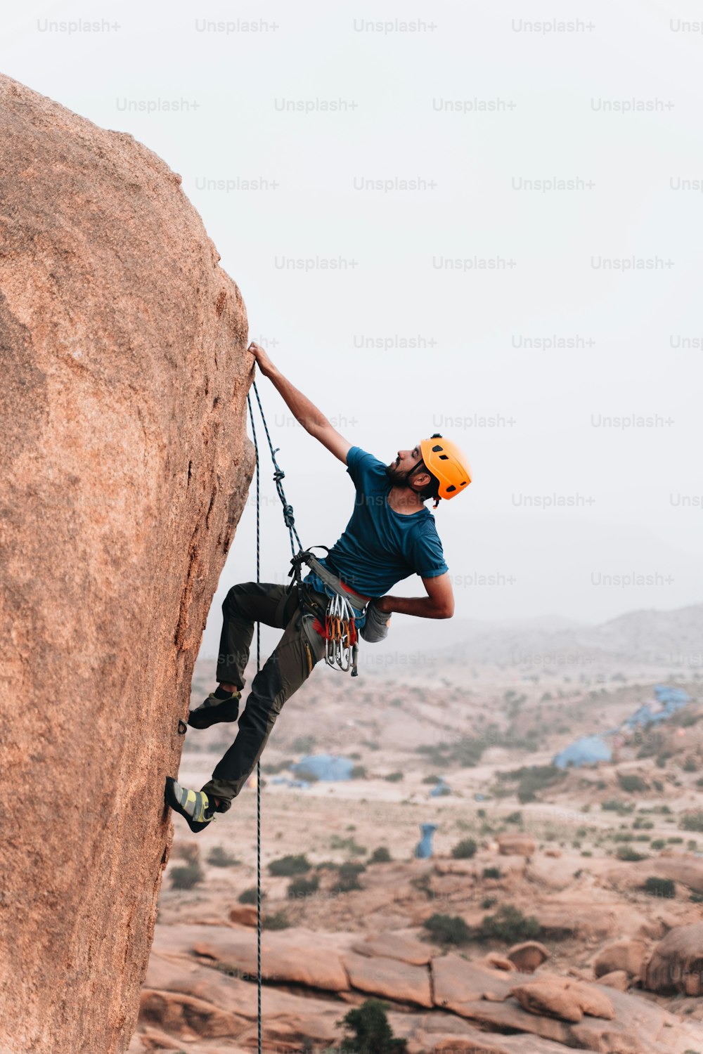 Un uomo che si arrampica sul fianco di una grande roccia