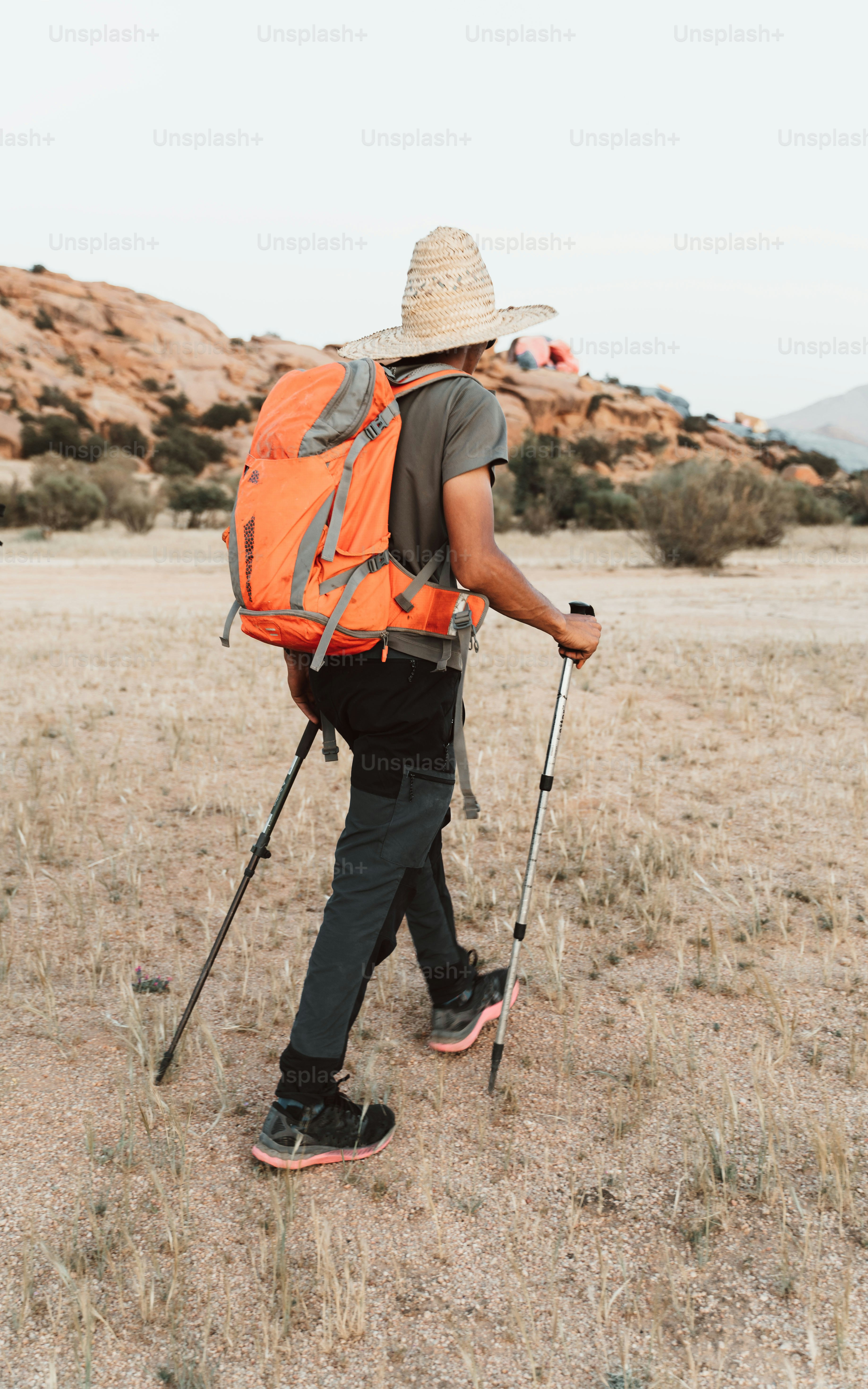 a man walking across a dry grass covered field
