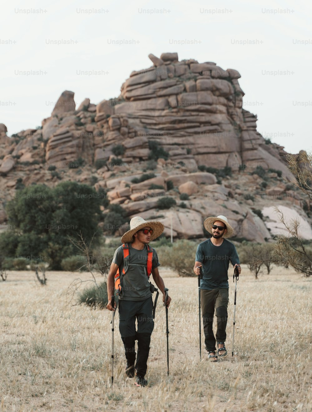 a couple of men walking across a dry grass field